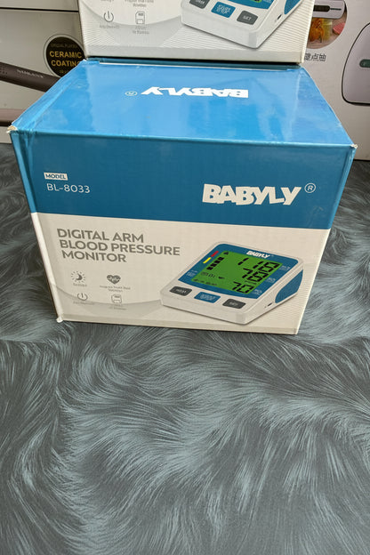 Box of BABYLY digital arm blood pressure monitor on a textured surface