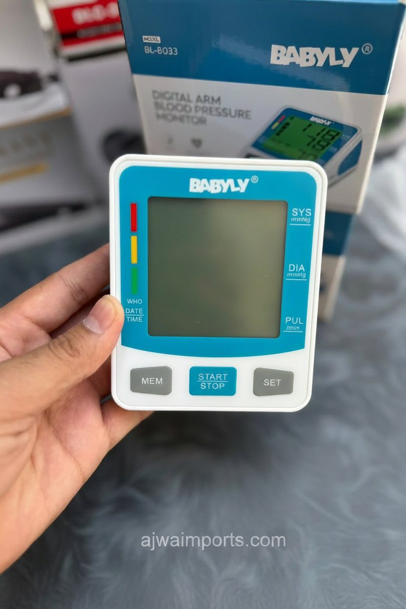 Digital arm blood pressure monitor held by a hand with packaging in the background.